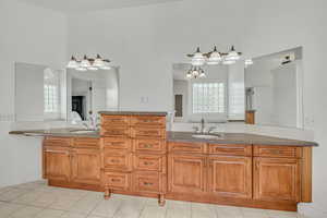 Full bath with two vanities, light tile patterned floors, and a chandelier