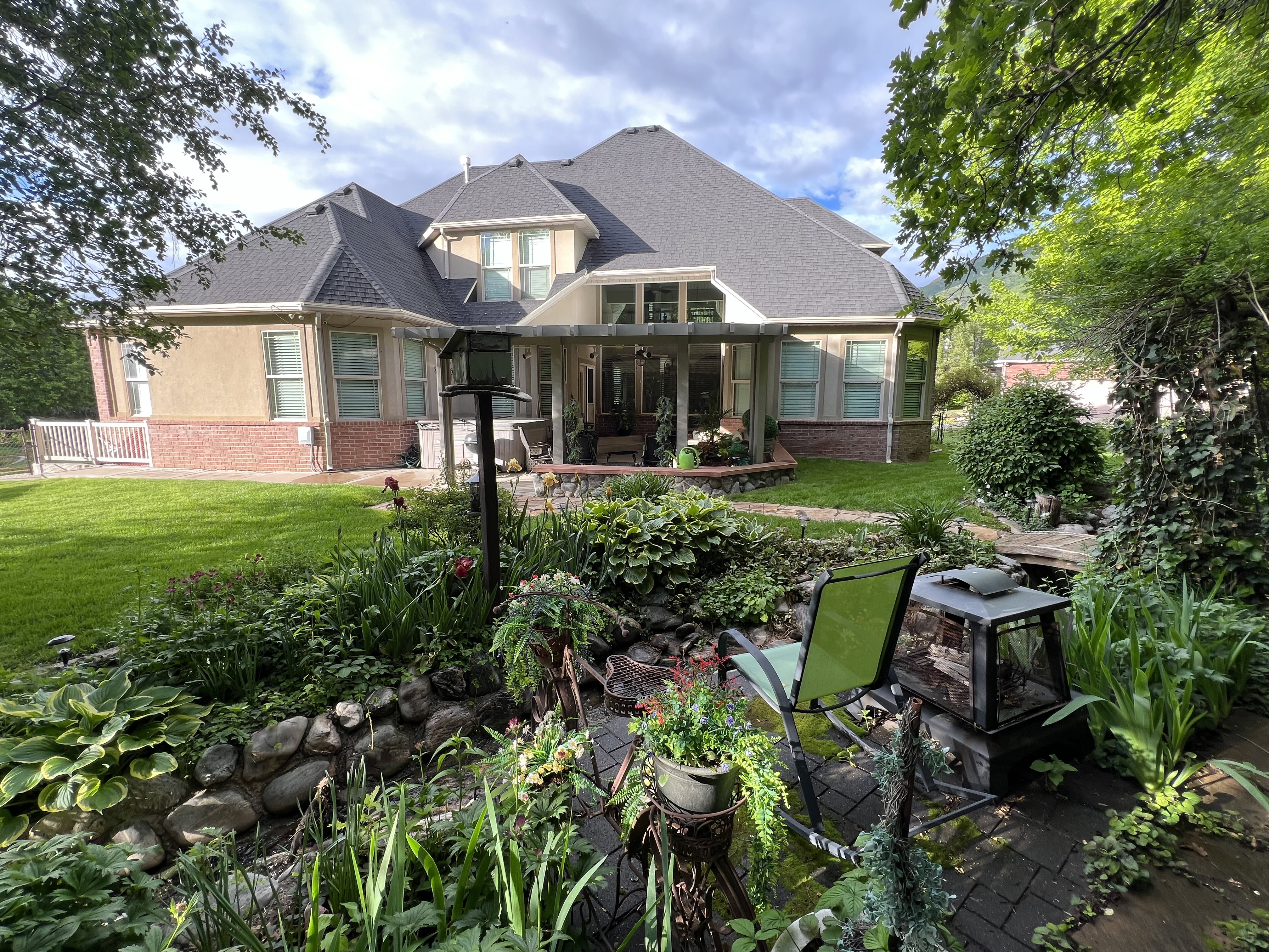 Back of property featuring brick siding, a lawn, a shingled roof, stucco siding, and a patio