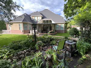 Back of property featuring brick siding, a lawn, a shingled roof, stucco siding, and a patio