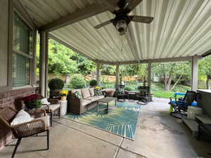 Fenced backyard with an outdoor hangout area, a patio, and a ceiling fan