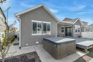 Rear view of property with stucco siding and a hot tub