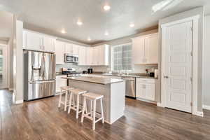 Kitchen featuring stainless steel appliances, recessed lighting, a kitchen breakfast bar, a kitchen island, and white cabinetry