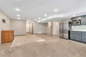 Finished basement featuring freestanding refrigerator and recessed lighting