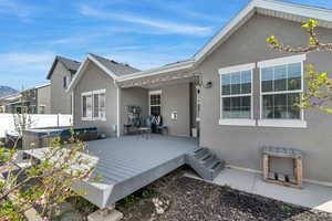 Back of house with stucco siding, a hot tub, and a deck