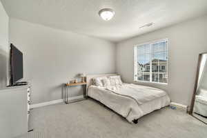 Bedroom with light carpet and a textured ceiling