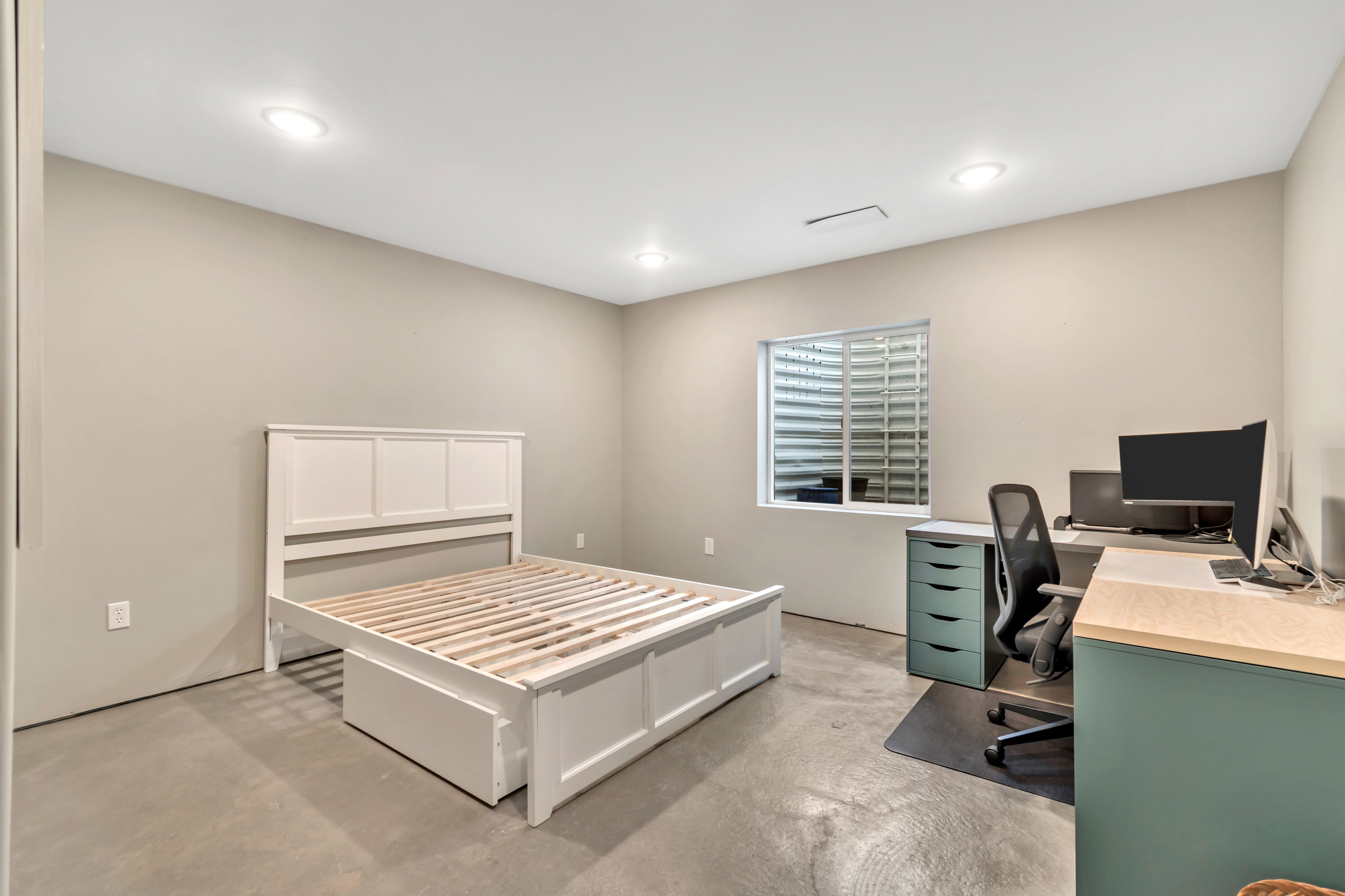 Bedroom with an office area, concrete floors, and recessed lighting