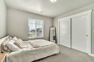 Bedroom with carpet floors, a textured ceiling, and a closet
