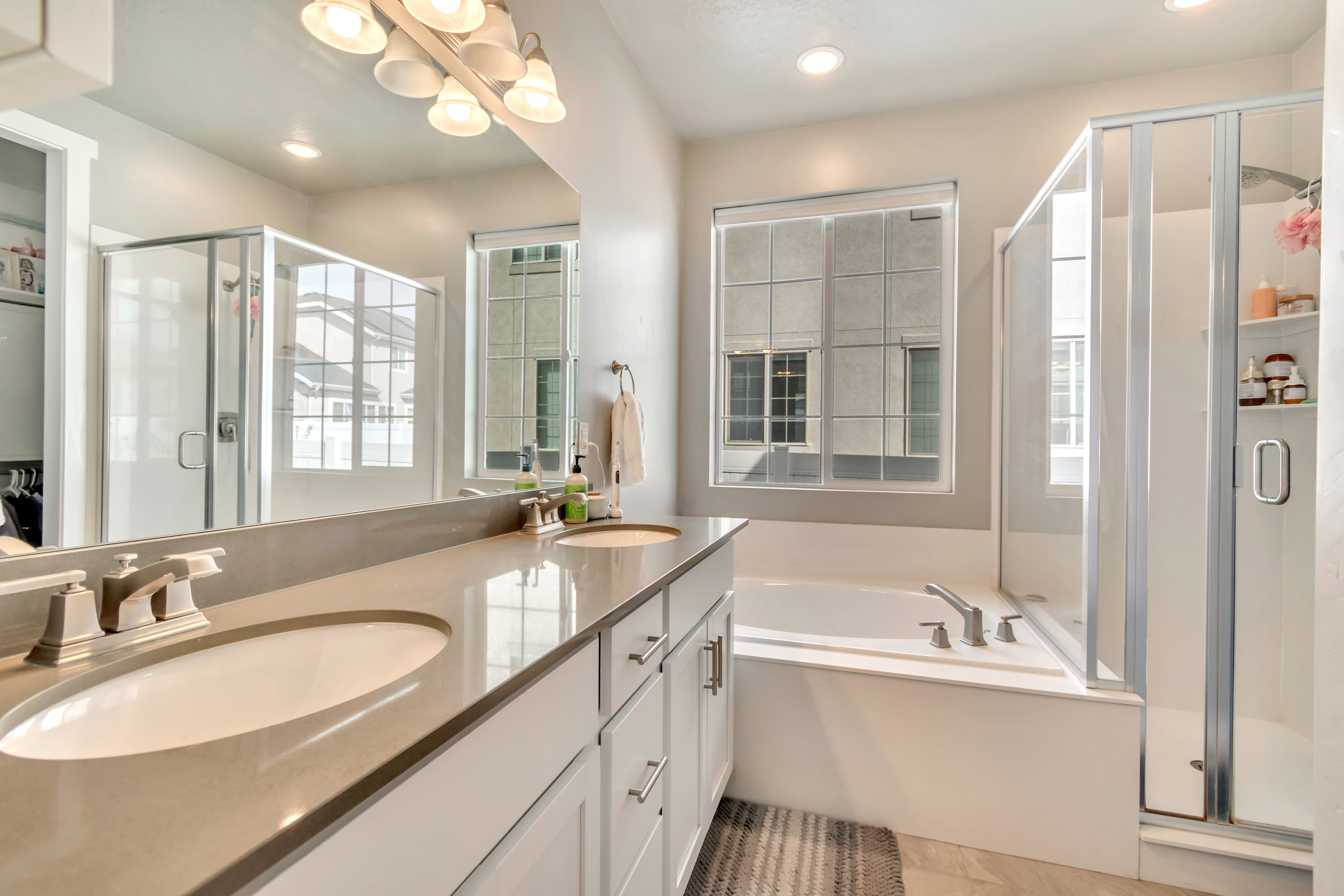 Full bath with a stall shower, double vanity, a bath, and suspended lighting