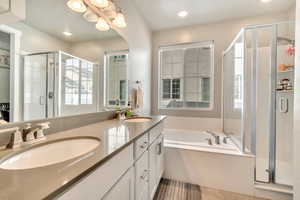 Full bath with a stall shower, double vanity, a bath, and suspended lighting