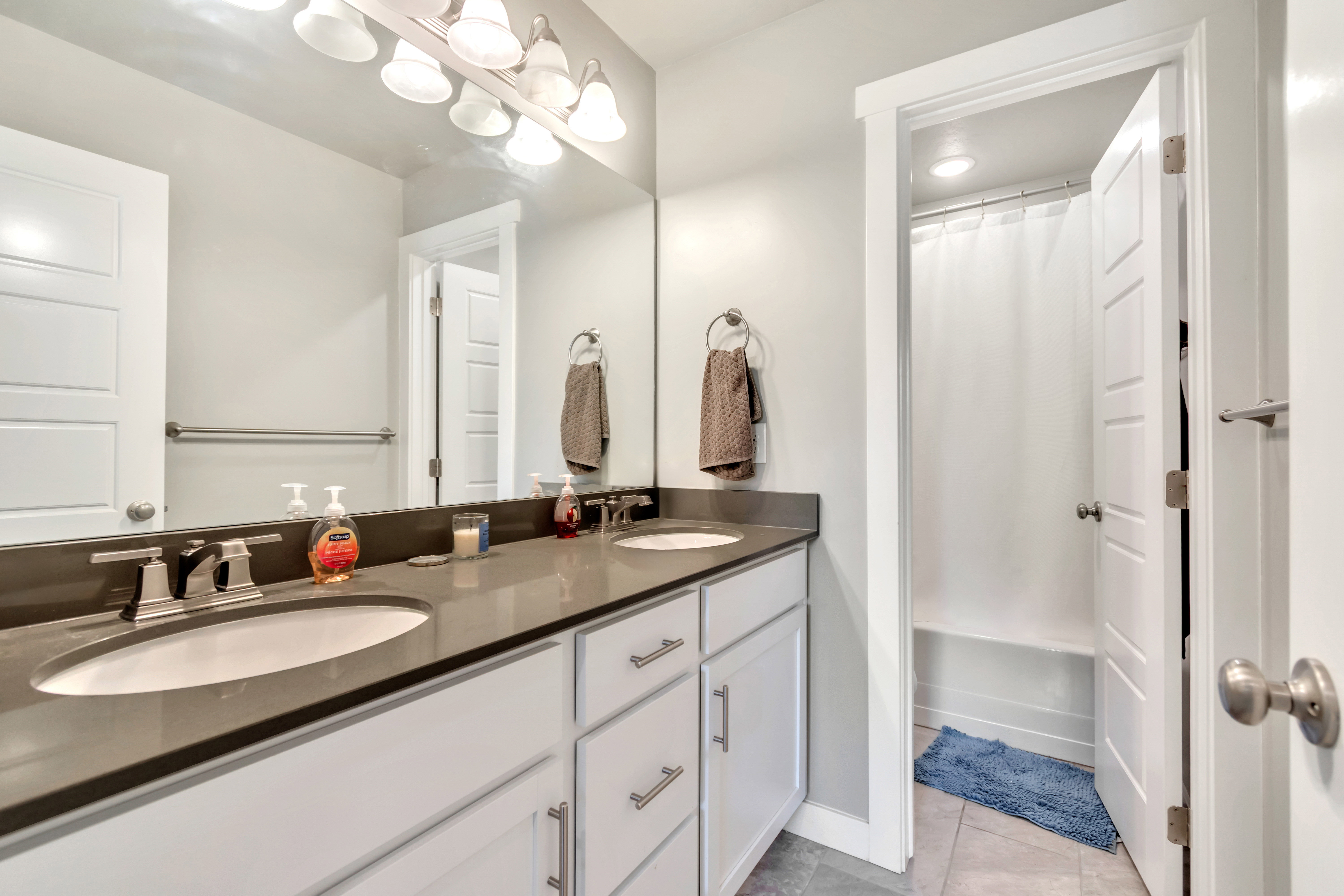 Bathroom with double vanity, light tile patterned floors, and shower / bath combo