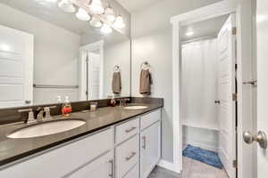 Bathroom with double vanity, light tile patterned floors, and shower / bath combo