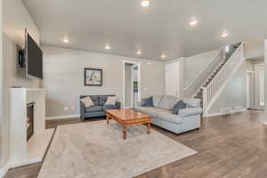 Living area with dark wood-style flooring, a lit fireplace, recessed lighting, and a textured ceiling