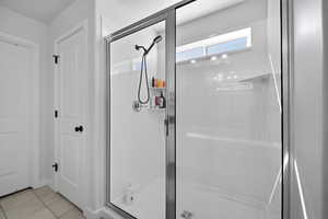 Bathroom with a shower stall and light tile patterned floors