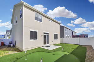 Rear view of property featuring a fenced backyard, a patio area, stucco siding, and an area to practice putting