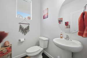Half bathroom with toilet and baseboards