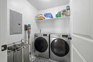 Laundry area featuring electric panel, washer and clothes dryer, and light tile patterned floors