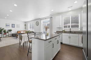 Kitchen with a breakfast bar, dark stone counters, a center island, open floor plan, and white cabinetry