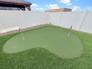 Fully fenced backyard is designed for easy living with maintenance-free xeriscaping, high-end turf, and even a built-in putting green