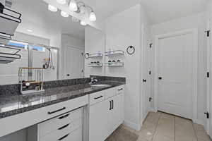 Bathroom with vanity, light tile patterned floors, and a stall shower