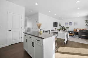 Kitchen with a kitchen bar, open floor plan, a center island, white cabinetry, and dark stone counters