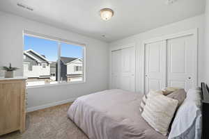 Carpeted bedroom with multiple closets and baseboards