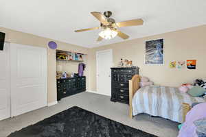 Bedroom featuring light colored carpet, ceiling fan, and a closet