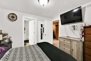Bedroom with a textured ceiling and light carpet