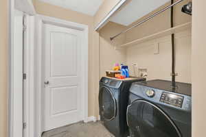 Laundry area featuring light colored carpet and washing machine and dryer