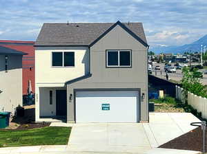View of front of house featuring a shingled roof, an attached garage, and driveway