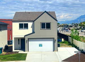 View of front facade featuring a garage, a shingled roof, driveway, and a mountain view