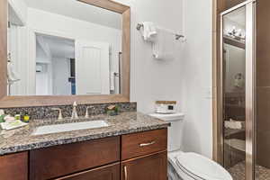 Bathroom featuring a stall shower, vanity, and a textured wall