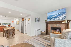Living room with a tile fireplace, heating unit, recessed lighting, and wood tiled floors