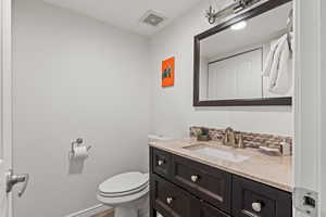 Half bath featuring vanity, a textured wall, and tasteful backsplash