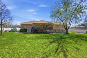 Back of property with a fenced backyard, brick siding, a patio, and a balcony