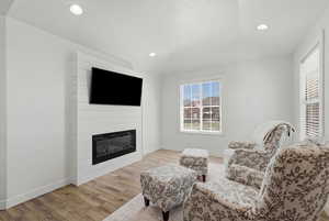 Sitting room featuring light wood finished floors, a fireplace, and recessed lighting