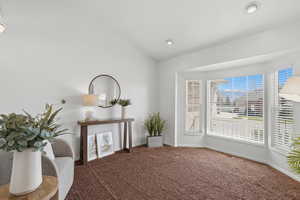Sitting room with vaulted ceiling and carpet