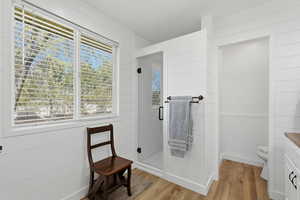 Full bathroom with wooden walls, vanity, a shower stall, and light wood-style flooring