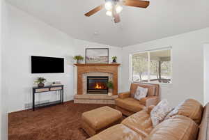 Living area with carpet, a glass covered fireplace, ceiling fan, and lofted ceiling