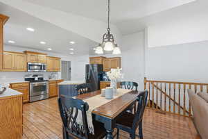 Dining room featuring light wood-style floors, lofted ceiling, and a chandelier