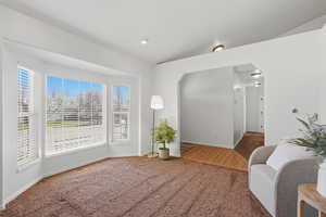 Sitting room featuring arched walkways, carpet, and lofted ceiling