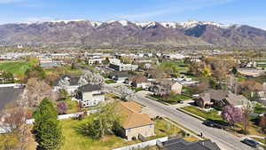 Aerial view of property and surrounding area featuring mountains and nearby suburban area