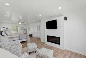 Bedroom with light wood-style flooring, ceiling fan, a fireplace, and recessed lighting