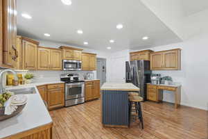 Kitchen featuring stainless steel appliances, a kitchen bar, light wood-style floors, a kitchen island, and recessed lighting
