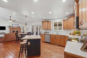 Kitchen with open floor plan, a kitchen island, a lit fireplace, stainless steel appliances, and a kitchen breakfast bar