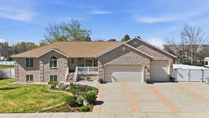 View of front facade featuring a garage, a gate, concrete driveway, and brick siding