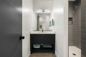 Full bath with vanity, a tile shower, and dark tile patterned floors