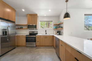 Kitchen featuring open shelves, stainless steel appliances, a peninsula, and light stone countertops
