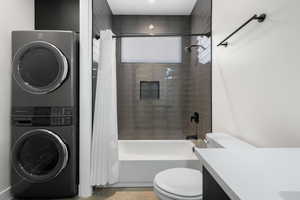 Full bathroom featuring vanity, stacked washer / dryer, and shower / tub combo with curtain