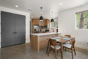 Kitchen with pendant lighting, stainless steel appliances, a peninsula, wood finish cabinets, and modern cabinets