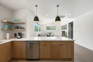 Kitchen featuring a peninsula, dishwasher, light stone countertops, lofted ceiling, and open floor plan